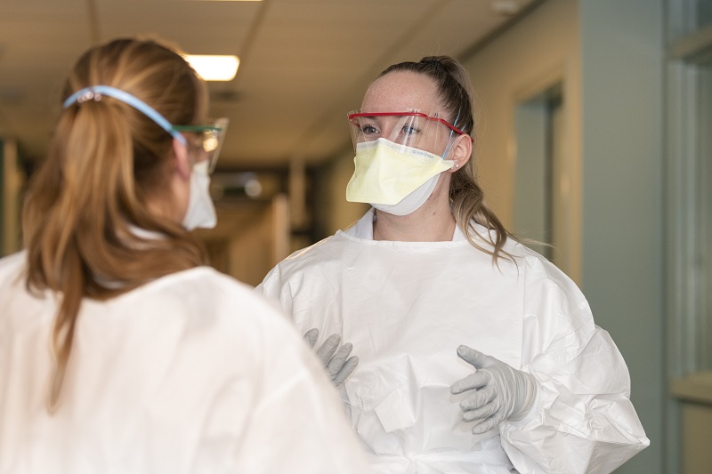 Verpleegkundigen met persoonlijke beschermingsmiddelen in gesprek