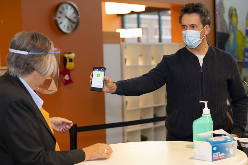 Bezoeker laat telefoon met coronavragenlijst zien